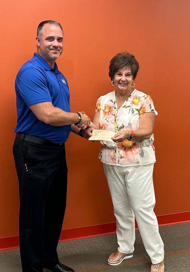 Jason Rollins presents a donation check to Claire Gatti Principal of St. Michael the Archangel School